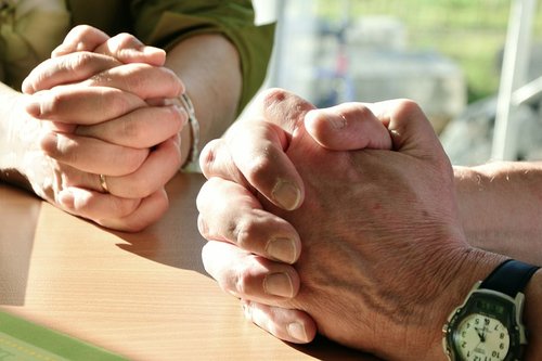 Naisen ja miehen rukoilevat kädet.