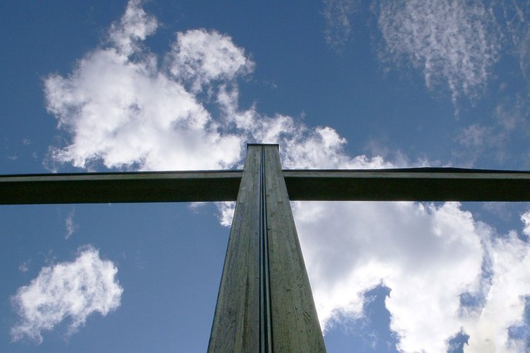 Risti kuvattuna ristin juurelta ylöspäin, jolloin näkyy risti ja sininen taivas.